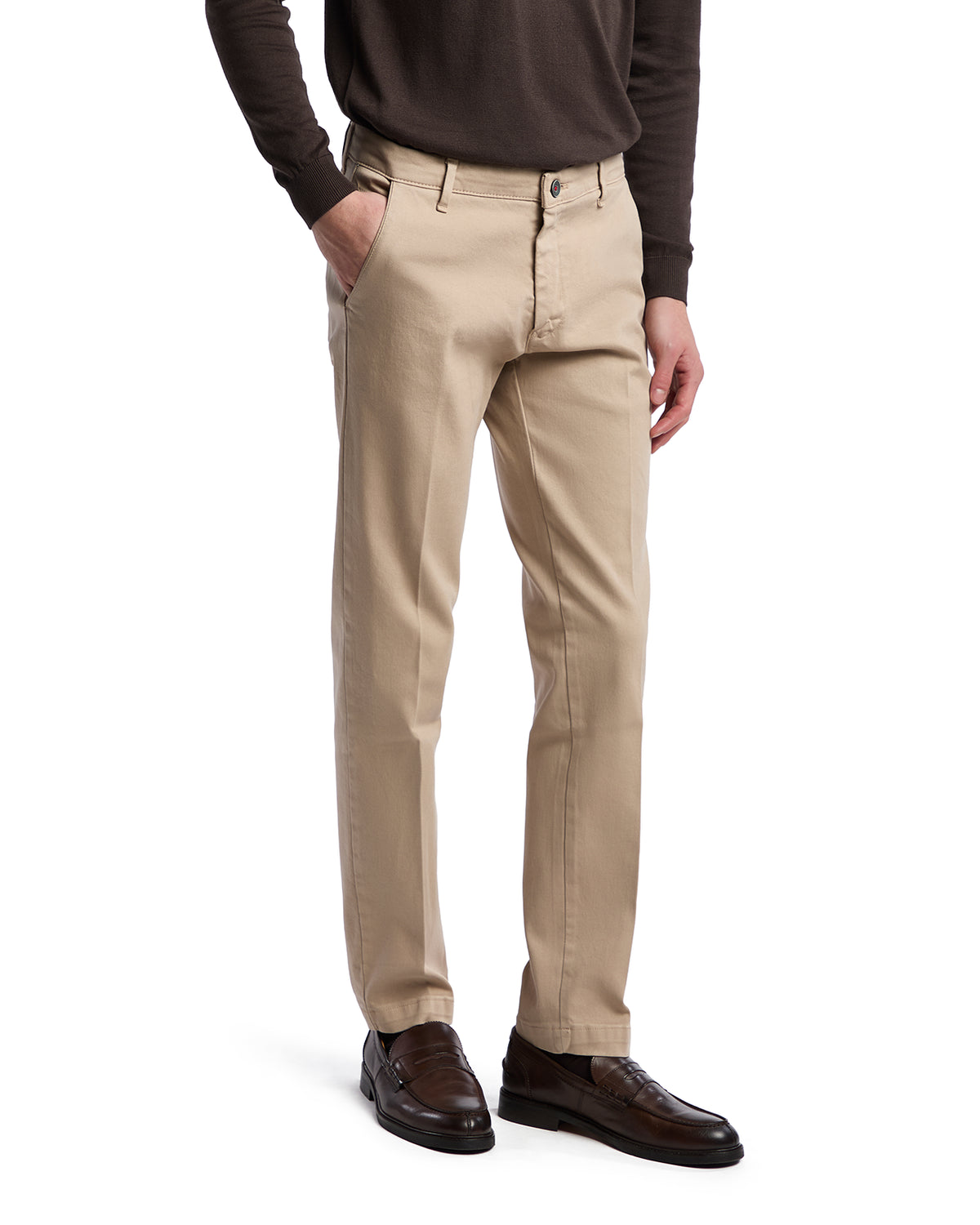 Men's beige chinos in stretch cotton with a slim fit, paired with a dark sweater and brown dress shoes.